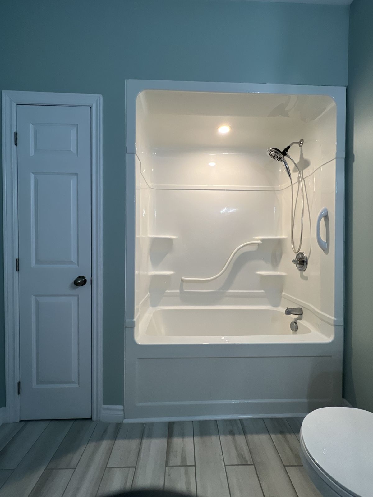 Bathroom before renovation, with a one-piece white acrylic tub and shower surround